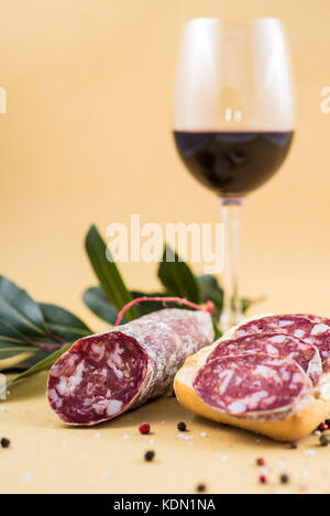 Scheiben der italienische Salami auf Brot und einige Gewürze und Rotwein Stockfoto