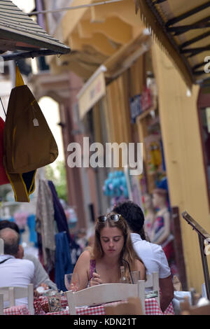 Eine junge Frau sitzt an einem Tisch zu Essen, eine griechische Taverne in Kerkira, Korfu, Griechenland. Stockfoto