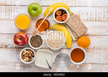 Gesunde Ernährung Ballaststoffe Quelle frühstück Haferflocken Honig Obst äpfel Bananen Orangensaft Wasser grüner Tee Muttern. Weiße Plank Holz Tisch. rustikal. Flach top Stockfoto