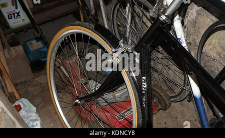 Oktober 2017 - Schwarzes Fahrrad in einem Schuppen mit einem alten Rasenmäher gelagert. Stockfoto