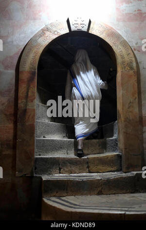 Eine katholische Nonne klettern Treppe der Kalvarienberg oder Golgatha traditionell als Ort der Kreuzigung Jesu und die grosszügig eingerichteten Teil der Kirche des heiligen Grabes in der Altstadt von Jerusalem Israel zu betrachten Stockfoto