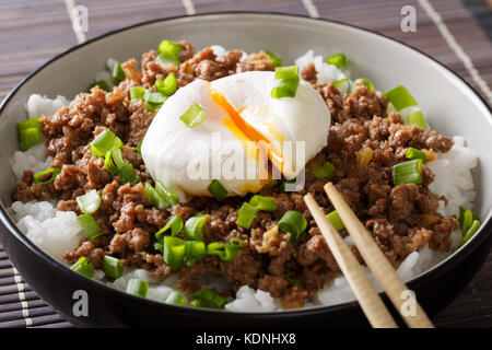 Japanisches Essen: Rindfleisch soboro mit Ei Pochierte, Reis und grüne Zwiebel close-up in einer Schüssel auf dem Tisch. Horizontale Stockfoto