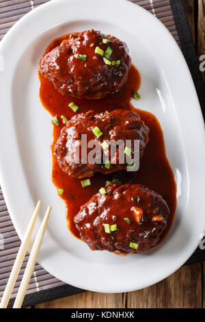 Japanisches Essen: hamburg Steak oder hambagu mit einer pikanten Sauce auf einer Platte close-up. Senkrechte Draufsicht von oben Stockfoto