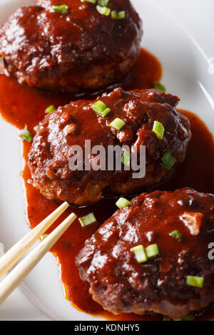 Japanisches Essen: hamburg Steak oder hambagu mit einer pikanten Sauce auf einer Platte close-up. Vertikale Stockfoto