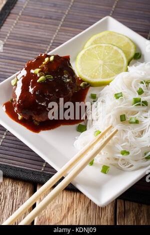 Japanische hamburg Steak oder hambagu mit Soße und Reis Nudeln close-up auf einem Teller auf den Tisch. Vertikale Stockfoto