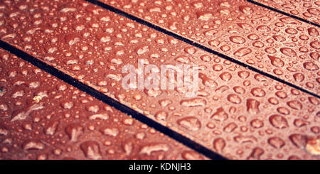 Holz- Oberfläche. Wassertropfen auf dem Holz. Kopieren Sie Raum. Parkbank hautnah. Farbe Oberfläche Makro Hintergrund. Stadt Gebäude Textur. Stockfoto