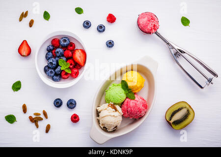 Bunte Eis mit gemischten Beeren Himbeere, Heidelbeere, Erdbeere, halbierte Kiwi und Pfefferminze setup auf weißem Hintergrund. Sommer und süßen Menü con Stockfoto