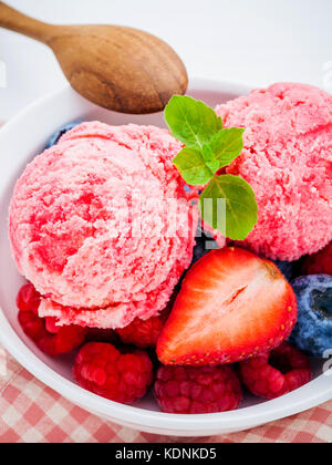 Nahaufnahme Eis mixed berry Früchte Himbeere, Heidelbeere, Erdbeere und Pfefferminze Blätter setup in Weiß Schüssel auf weißem Holz- Hintergrund. Sommer ein Stockfoto