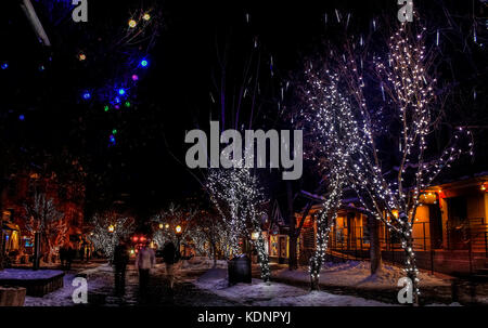 Night Street in der Innenstadt von Aspen, Colorado, Mit Weihnachtsbeleuchtung und Dekoration eingerichtet. Unscharfe Figuren von Menschen zu Fuß entlang der Straße; Usa Stockfoto
