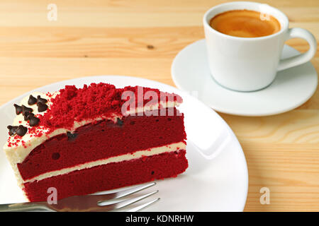 Red velvet shortcake mit Cream Cheese frosting und eine Tasse heißen Kaffee im Hintergrund Stockfoto