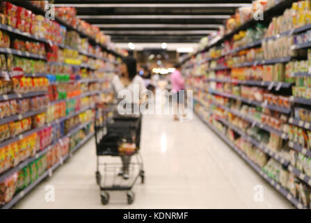 Unscharf Schoß einer Frau mit ihrem Warenkorb am Lebensmittelgeschäft Regal im Supermarkt auf der Suche Stockfoto