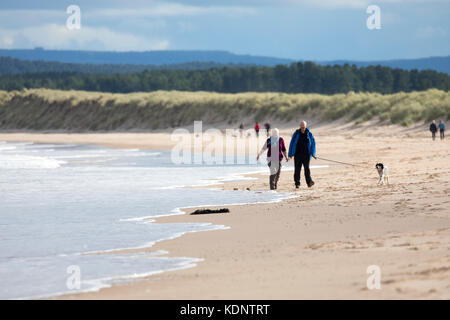 Wanderer geniessen Herbst Sonne auf den Sandstrand an der malerischen Badeort Lossiemouth, Schottland Stockfoto