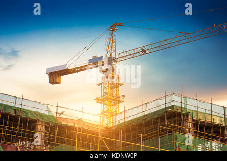 Industrielle Baukräne und Gebäude Silhouetten über Sun bei Sonnenaufgang. Stockfoto