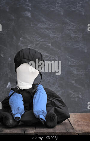 Kleine Hand gemacht Amish Puppe gegen eine rustikale Hintergrund sitzen Stockfoto