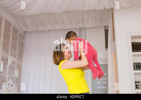 Glückliche Familie. Mutter wirft durcheinander Rennen Baby, zu Hause spielen Stockfoto