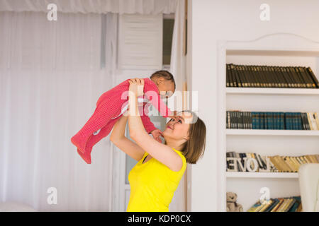 Glückliche Familie. Mutter wirft durcheinander Rennen Baby, zu Hause spielen Stockfoto