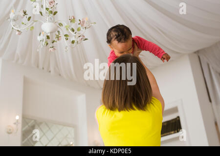 Glückliche Familie. Mutter wirft durcheinander Rennen Baby, zu Hause spielen Stockfoto