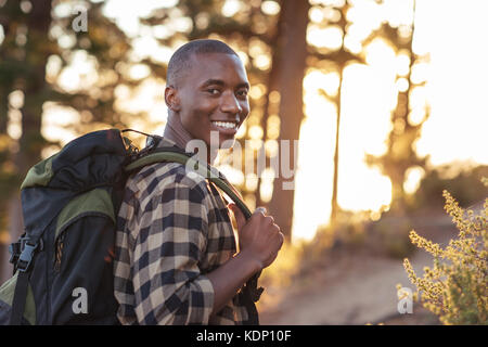 Lächelnden jungen afrikanischen Mann Wandern auf einem Trail in der Dämmerung Stockfoto