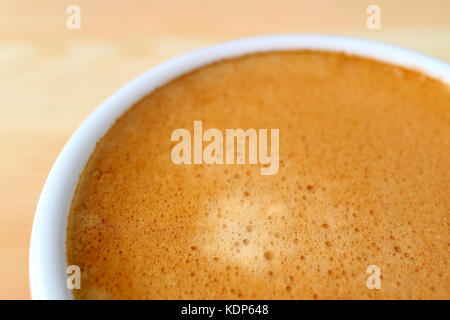 Bis aromatischen italienischen Espresso Schaum in Weiß Kaffeetasse geschlossen, mit selektiven Fokus und unscharfen Hintergrund Stockfoto