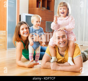 Portrait eines glücklichen normalen Familie mit zwei Kindern auf dem Fußboden im Wohnzimmer Stockfoto