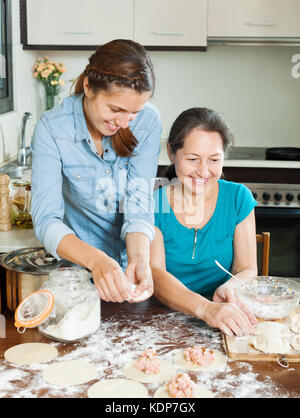 Lachende Frauen, die Kuchen oder Fleisch Knödel zu Hause Küche Stockfoto