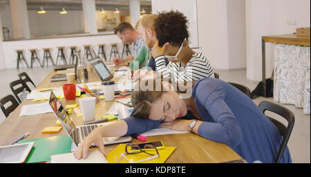 Müde Arbeiter am Tisch im Büro Stockfoto