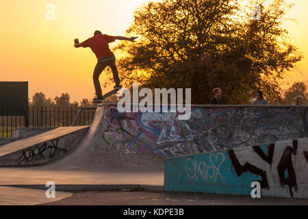 Skateboarder, BMX und Roller Fahrer bei einem städtischen Skatepark in London, da die Sonne untergeht Stockfoto