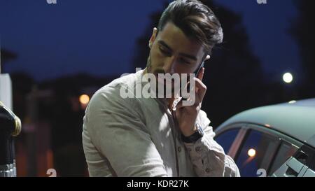 Junger Mann mit seinem Auto tanken an der Tankstelle Stockfoto