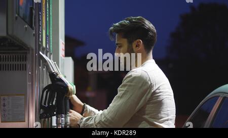 Junger Mann mit seinem Auto tanken an der Tankstelle Stockfoto