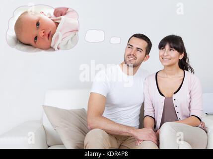 Junge glückliches Paar auf dem Sofa träumen, Baby sitzen zusammen Stockfoto