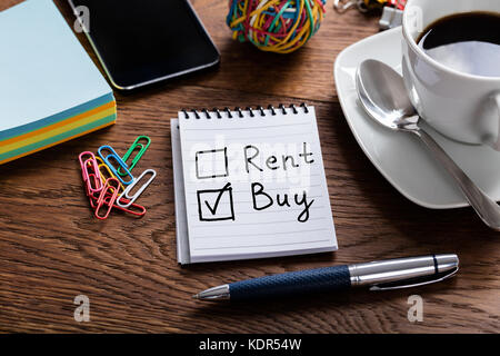 Hohe Betrachtungswinkel von Notepad auswählen Kaufen Mieten Option auf hölzernen Schreibtisch Stockfoto