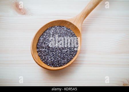 Nahrhafte Chia Samen in hölzernen Löffel für Ernährung Lebensmittel Zutaten setup auf Holz- Hintergrund. Stockfoto