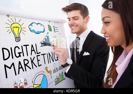 Zwei glückliche Geschäftsleute über digitales Marketing auf Flipchart Stockfoto