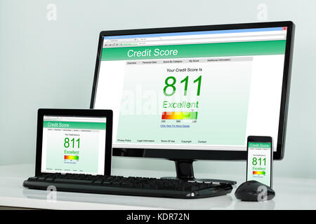 Computer Desktop mit digitalen Tablet und mobilephone Übersicht Credit Score online auf Büro Schreibtisch Stockfoto