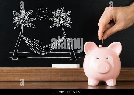 Nahaufnahme der Person Hand sparen Geld im Sparschwein für den Urlaub am Strand. Stockfoto