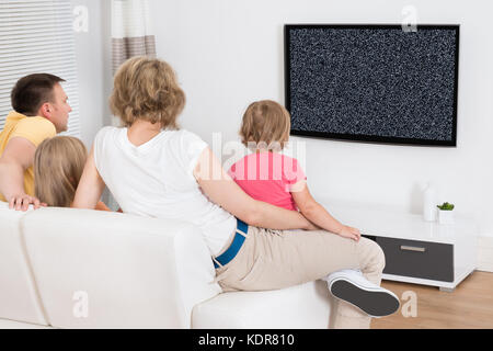 Familie Sitzt Auf Der Couch Und Schaut Gemeinsam Fernsehen Ohne Signal Zu Hause Stockfoto