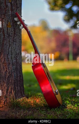 Kinder Gitarre lehnte sich gegen den Baum Stockfoto