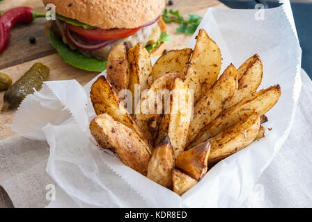 Gebackene Kartoffeln mit Gewürzen und Kräutern aus weißem Papier serviert - bereit zu essen Stockfoto