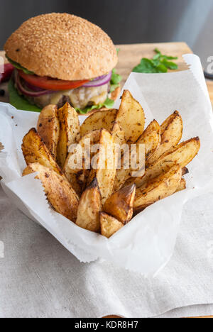 Gebackene Kartoffeln mit Gewürzen und Kräutern aus weißem Papier serviert - bereit zu essen Stockfoto