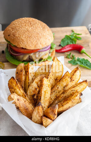 Gebackene Kartoffeln mit Gewürzen und Kräutern aus weißem Papier serviert - bereit zu essen Stockfoto