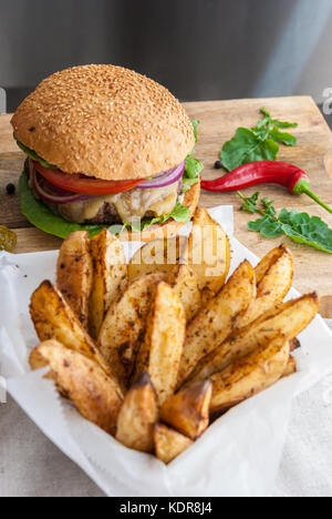 Gebackene Kartoffeln mit Gewürzen und Kräutern aus weißem Papier serviert - bereit zu essen Stockfoto