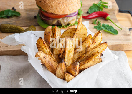 Gebackene Kartoffeln mit Gewürzen und Kräutern aus weißem Papier serviert - bereit zu essen Stockfoto
