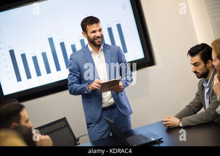 Junge attraktive Geschäftsmann mit Präsentation zu seinen Kollegen Stockfoto