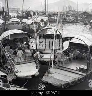 Aus den 1950er Jahren stammende, historische Mütter mit ihren Kindern auf ihren Dschunken (Booten), die im schwimmenden Dorf Aberdeen, Hafen von Aberdeen, Hongkong, festgemacht sind. Stockfoto