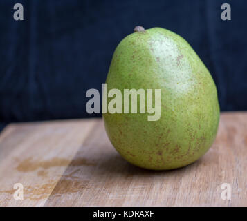 Eine einzelne bartlett Grüne und rote Birne auf einem Schneidebrett. Stockfoto