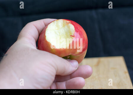 Apple in einer männlichen Hand mit Biss heraus genommen zu werden. Stockfoto