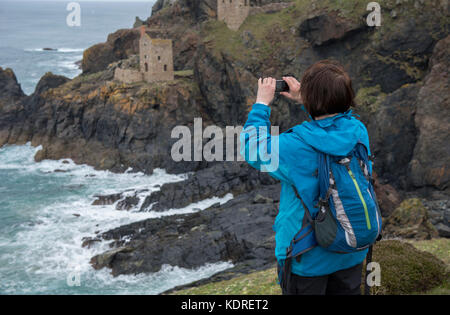 Frau mit ihrem Handy ein Foto von der Crown Mines Botallack, Cornwall, England, Großbritannien zu nehmen Stockfoto
