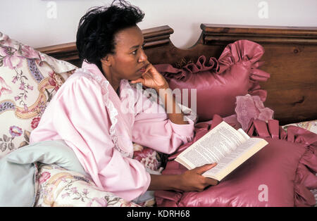 Attraktive, reife Frau midlife im mittleren Alter 40-50 Jahre alten Entspannen im Bett von Buch © Myrleen Pearson abgelenkt Stockfoto