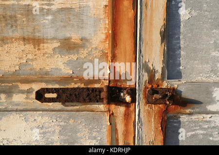 Detail des alten Türen mit abblätternder Farbe und rostige Klinke. Alter und Verfall. Stockfoto