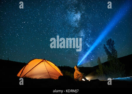 Man Touristen mit Taschenlampe in der Nähe seiner camp Zelt in der Nacht. Stockfoto